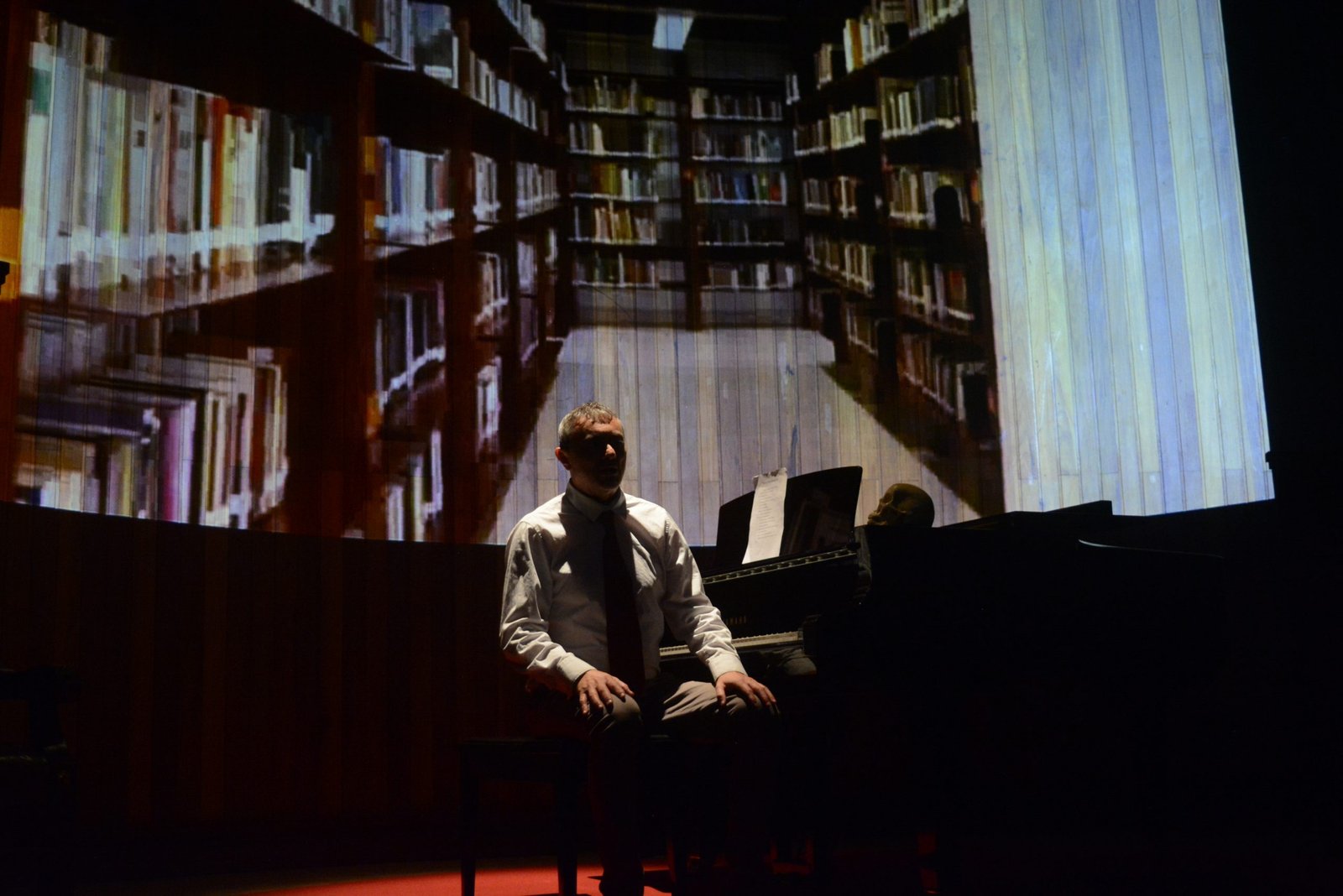 Homem sentado, em cena, na peça "Trevas Ao meio-Dia: Uma paisagem cênico-musical sobre a poética de Augusto dos Anjos"