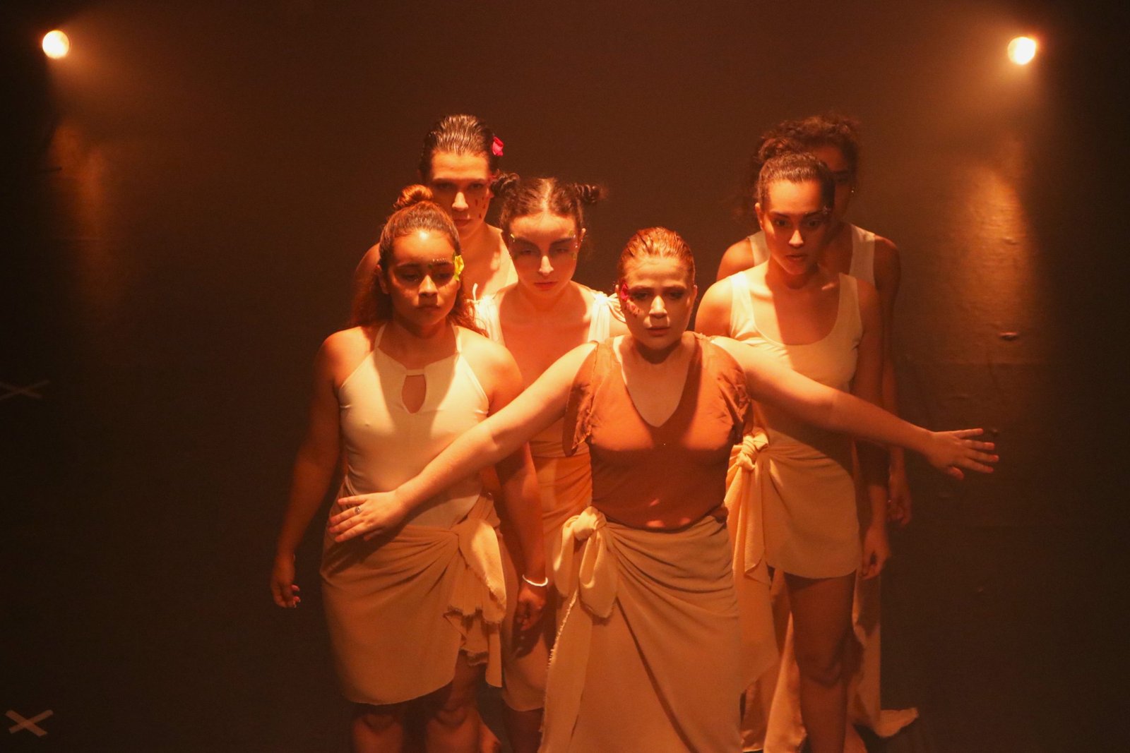 Foto colorida em luz amarela mostrando estudantes da SP Escola de Teatro em experimento cênico