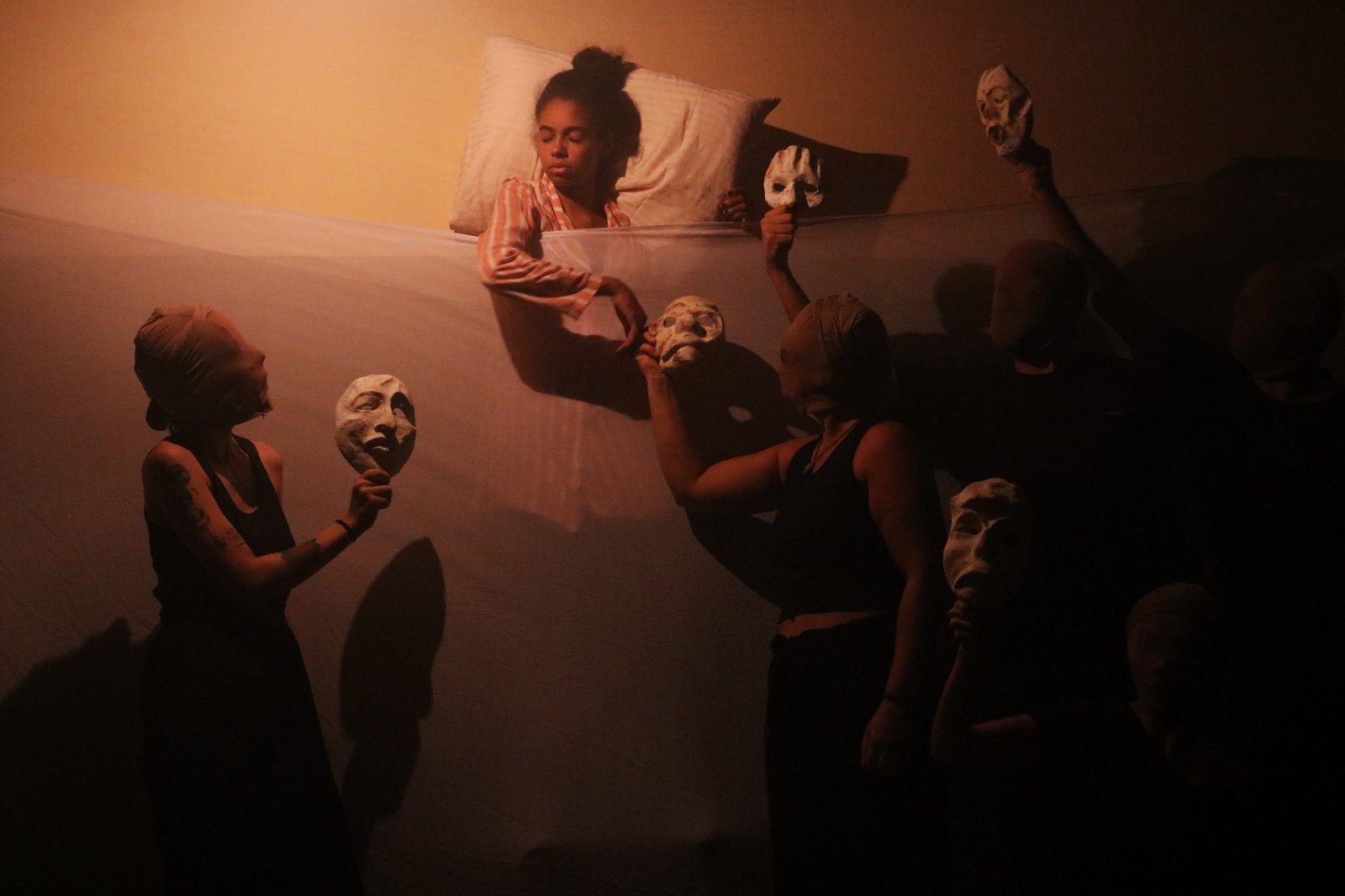 Foto colorida mostrando estudantes da SP Escola de Teatro segurando máscaras teatrais em experimento cênico