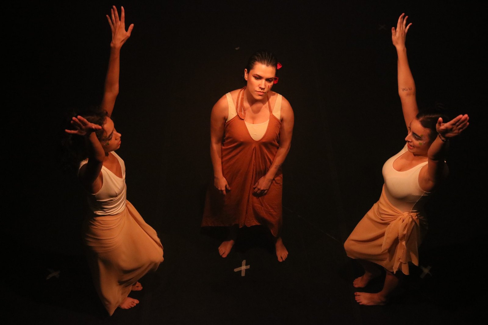 Foto colorida com três estudantes da SP Escola de Teatro em experimento cênico