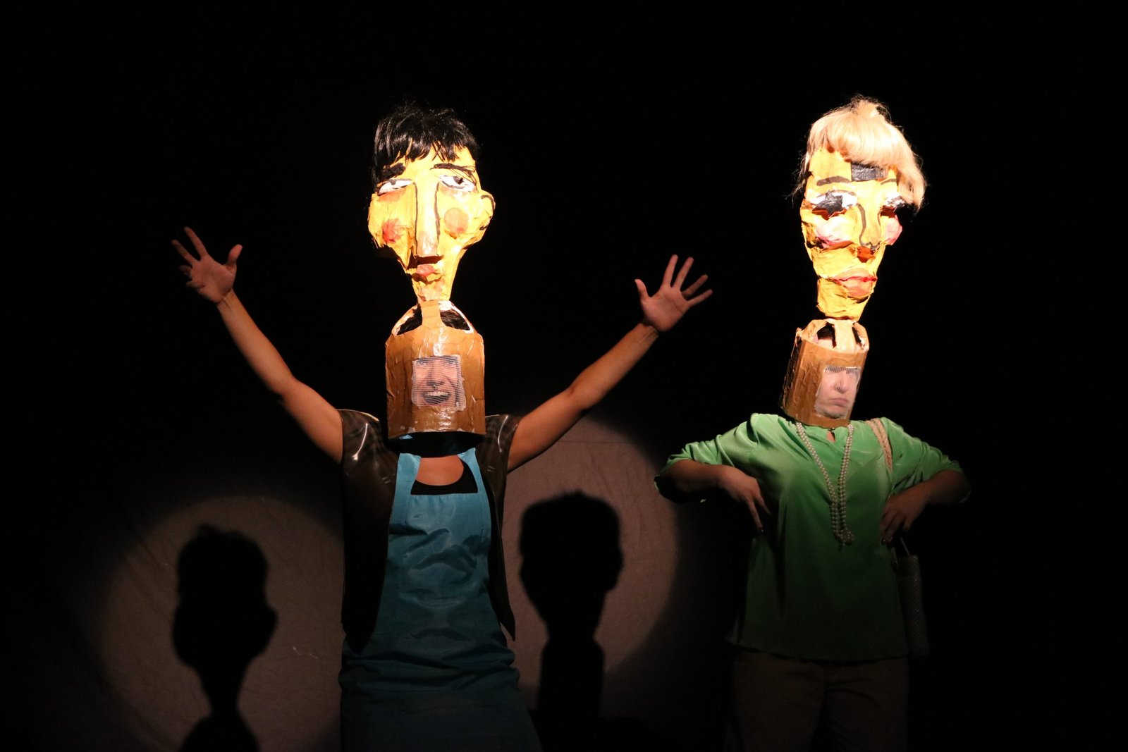 Foto colorida mostrando dois estudantes da SP Escola de Teatro com máscara em suas cabeças em experimento cênico