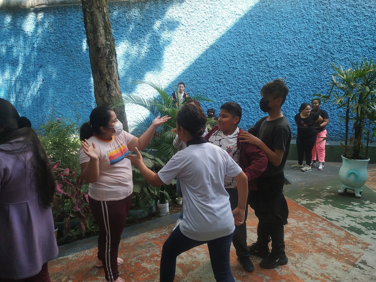Fotografia colorida mostrando quatro estudantes da E.E. Eduardo Prado em oficina de jogos teatrais