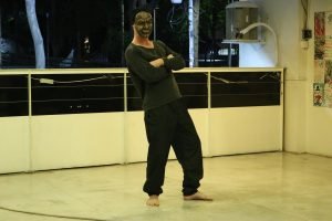 Fotografia colorida mostrando Miguel Rosa com uma máscara em aula-espetáculo no lançamento do livro