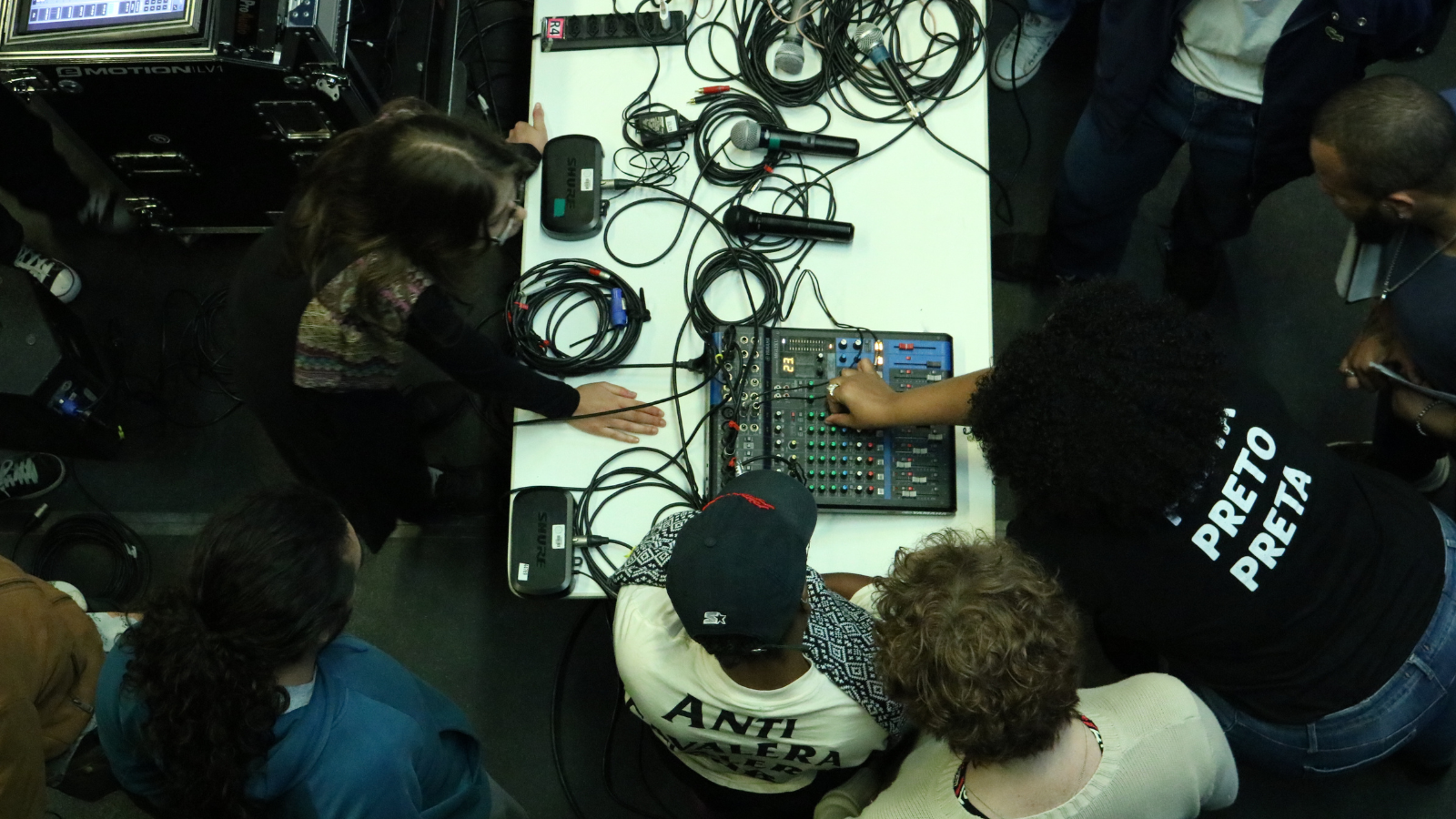 Fotografia colorida de Allyne Cassini mexendo numa mesa de som para a turma de sonoplastia