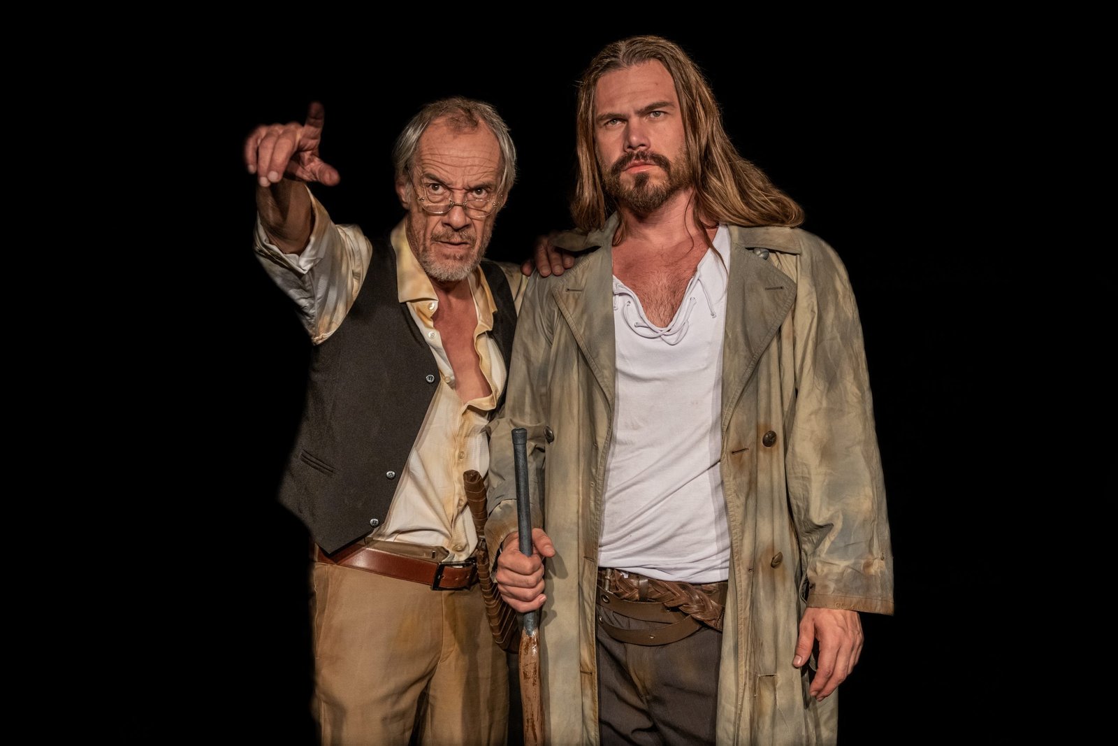 Imagem colorida de dois homens atores em cena, na peça As Bruxas de Salém