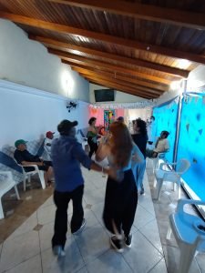 Fotografia colorida dos estudantes da SP Escola de Teatro na atividade de contrapartida no Centro de Acolhida Especial para Idosos do Brás