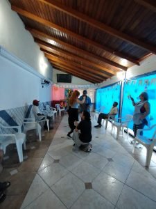 Fotografia colorida dos estudantes da SP Escola de Teatro na atividade de contrapartida no Centro de Acolhida Especial para Idosos do Brás