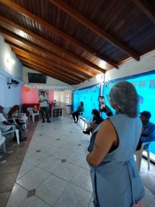 Fotografia colorida dos estudantes da SP Escola de Teatro na atividade de contrapartida no Centro de Acolhida Especial para Idosos do Brás