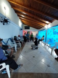 Fotografia colorida dos estudantes da SP Escola de Teatro na atividade de contrapartida no Centro de Acolhida Especial para Idosos do Brás
