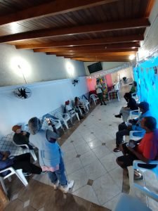 Fotografia colorida dos estudantes da SP Escola de Teatro na atividade de contrapartida no Centro de Acolhida Especial para Idosos do Brás