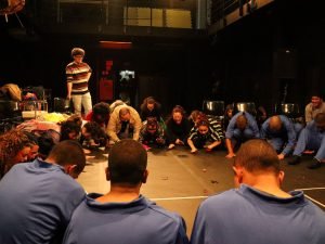 Fotografia de grupo de jovens da Fundação CASA assistindo experimento cênico