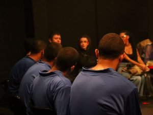 Fotografia de grupo de jovens da Fundação CASA assistindo experimento cênico